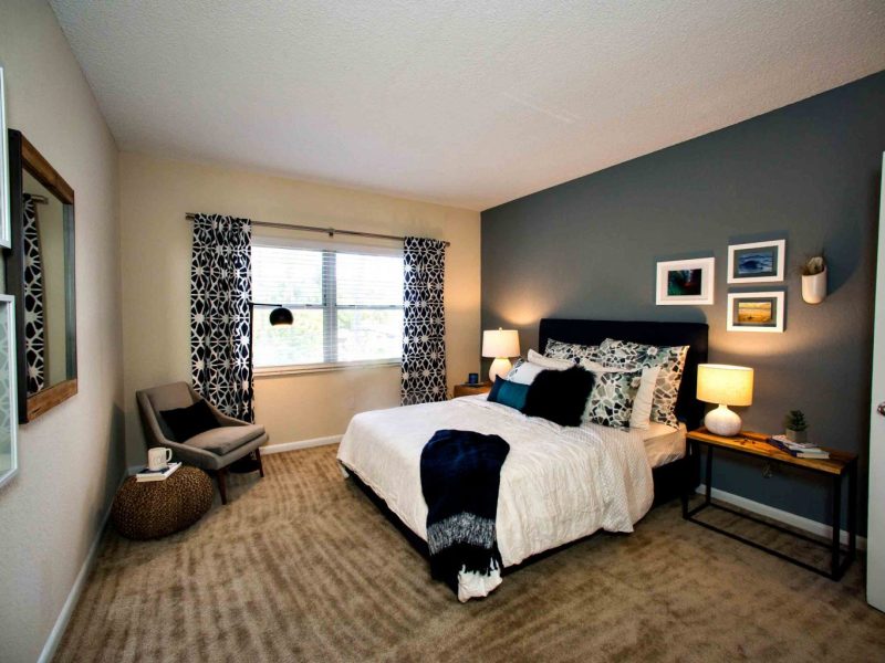 This image shows the Premium Apartment Feature, specifically the spacious bedroom area with elegant bedding and fabrics that was ideal for comfy living. The bedroom is also offering a partial Intracoastal view outside the apartment.