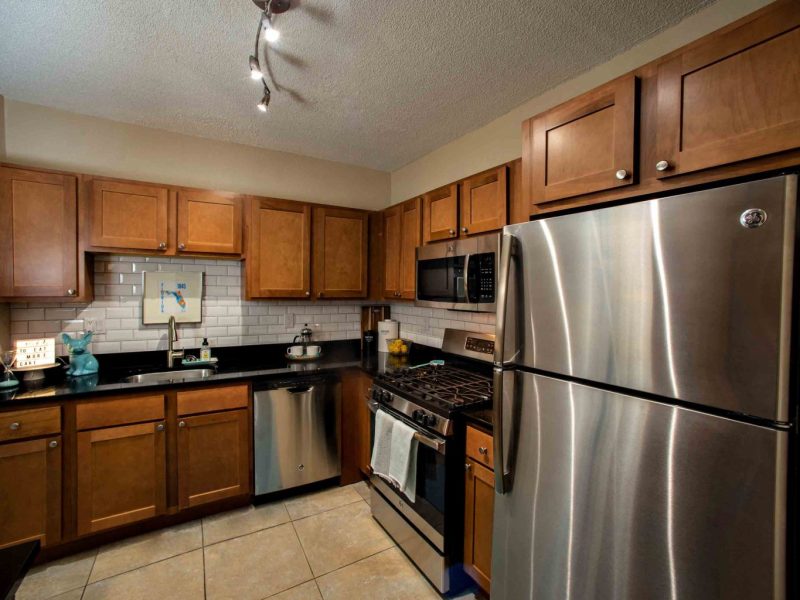This image shows the Premium Apartment Feature, especially the kitchen island showcasing a neat granite-inspired countertop, wooden cabinets, and stainless steel appliances.