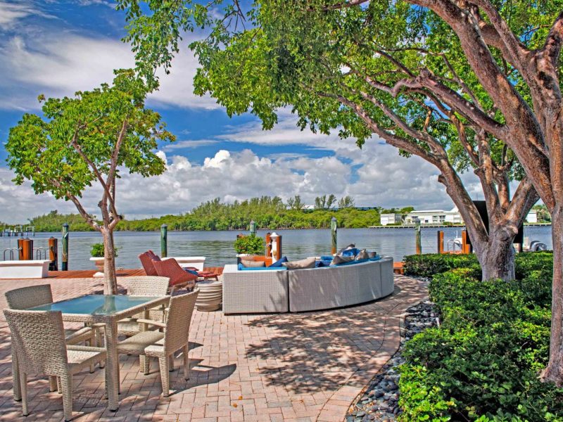 This image exhibits anexpansive view of the comfy outdoor lounge with a beautiful waterfront, a perfect place for relaxation with family and friends.